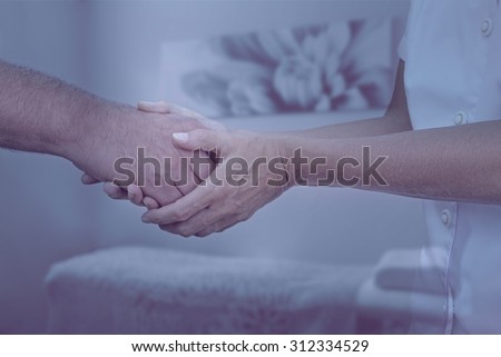 Therapist welcoming new patient - Female therapist holding hand of male client greeting him into therapy room with muted cool colors and soft focus background