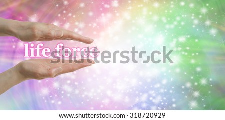 Your Life Force is in Your Hands - Female parallel hands with the words \'life force, floating between surrounded by a sparkles on a pastel colored  background and plenty of copy space