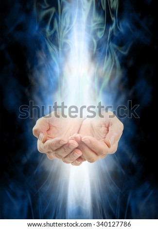 Receiving healing  -  Female cupped hands with white energy streaming  in from above and below on a swirling misty blue and green energy background