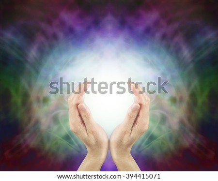 Pranic Healing Energy - female hands cupped around a ball of bright energy on a beautiful subtle multi colored energy field background with plenty of copy space
