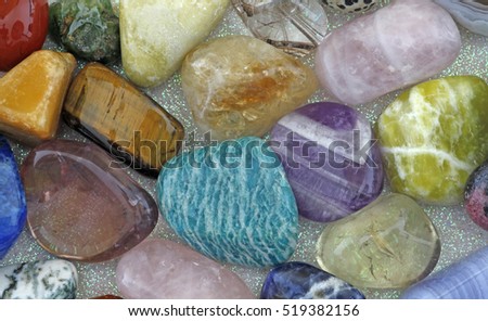 Close up of Healing Crystals - Various tumbled stones on an iridescent background including amazonite, ametrine, rose quartz, emerald, smokey quartz, citrine, jasper and tigers eye