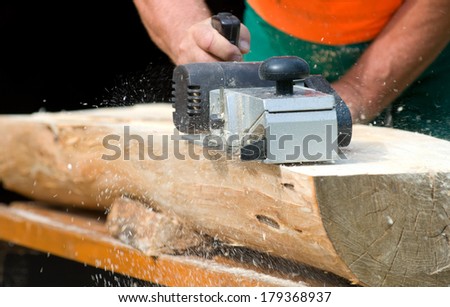 Carpenter with electric wood planer at work outdoor