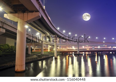 hanged-up highway road over Tokyo bay waters at night time with full moon in the sky