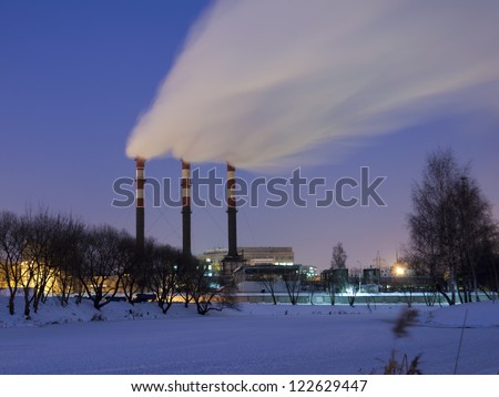 night industrial landscape with tall chimneys by winter time