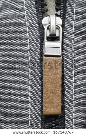 fragment of open plastic zipper fastener with brown leather tag