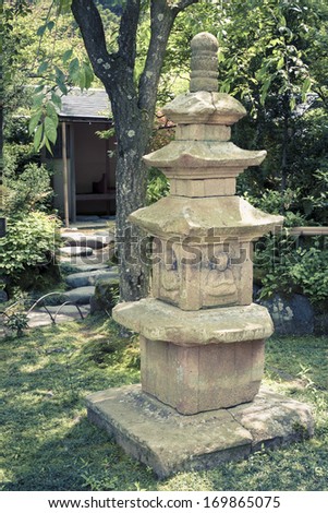 Japanese zen garden with ancient sculpture on green meadow