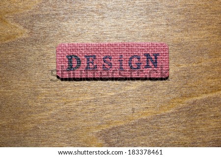 ink printed Design word on red canvas label laying on wooden surface