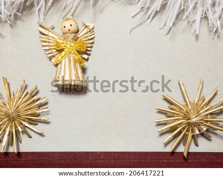 vintage toy angel figurine on old cardboard with straw snowflakes