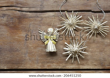 vintage toy angel figurine on weathered wooden table with straw snowflakes