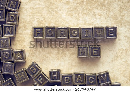 forgive me phrase made from metallic blocks over grunge paper background