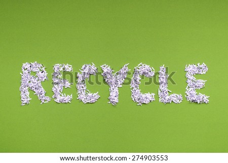 recycle word made from heap of shredded white paper over green