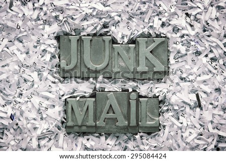 junk mail phrase made from metallic letterpress type inside of shredded paper heap