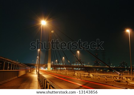 huge highway structure at suspension support by night in Tokyo, Japan with red car traces and walking man\'s silhouette ahead