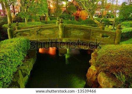 Japanese garden by night with traditional bridge over water pond at Asakusa, Tokyo, Japan