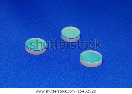 laser industry optical components ; flat thick mirrors with special reflection coating used in Laboratory Science and in Laser Manufacture on the blue canvas background