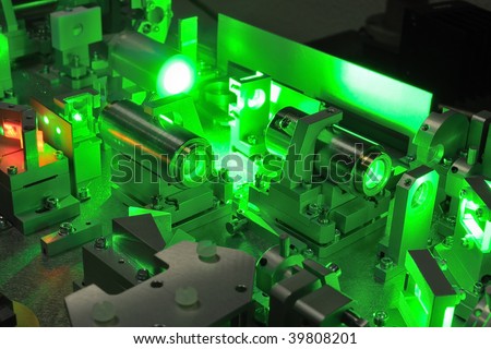 bright green laser light going inside complicate scientific system; selective focus on central part of image