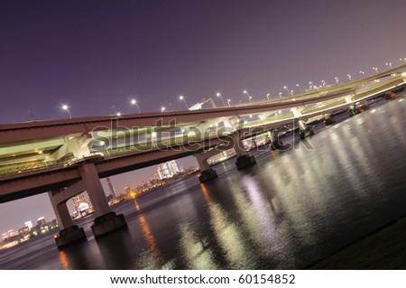 huge highway structure going through the night over river waters in Tokyo, Japan