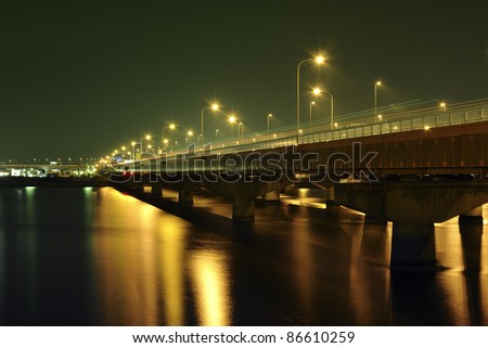 straight, well illuminated highway over river waters in Tokyo by night