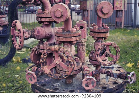 complicated rusty industrial pipe structure with many different pipe-wheels; focus on front wheel