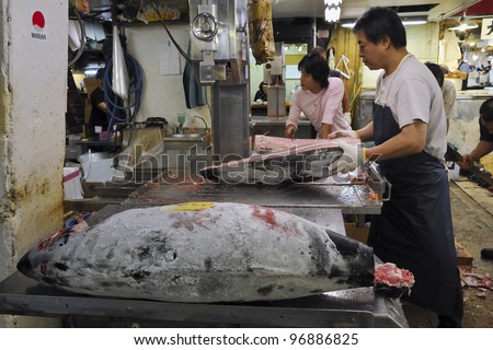 TOKYO, JAPAN - SEPTEMBER 27: worker cuts big frozen tuna fish body on the place of world famous Tokyo Tsukiji fish market on September 27, 2008 in Tokyo, Japan.