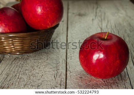juicy red apple on a wooden background on the background blurred basket with apples