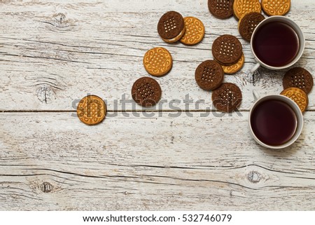 two cups of tea with  two-tone cookies on a light wooden background
