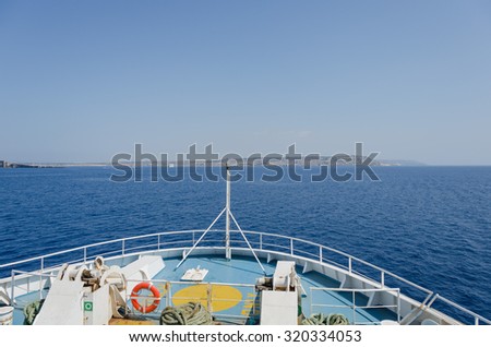 View to the sea, land and passing ship from the bow of the ship