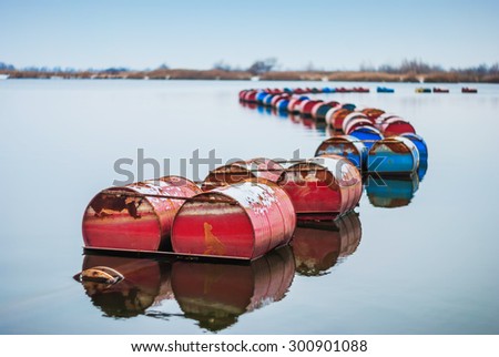 Red and blue rusty iron barrels in the water