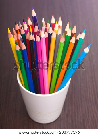 Cup with colorful Pencils on wooden table