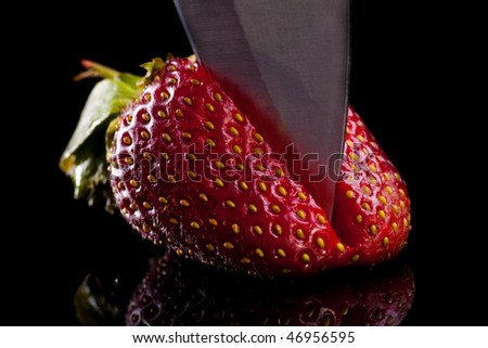 Cook cut strawberries in a glass desk. Isolated on black.