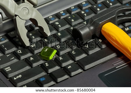 A broken laptop with a hammer and pliers. Closeup