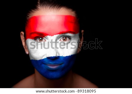 Portrait of a woman with the flag of the Netherlands painted on her face.
