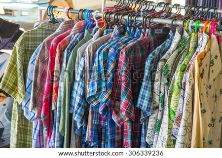 some used clothes hanging on a rack in a flea market