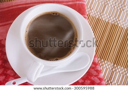 Hot coffee from the corner on a red cloth and bamboo blinds