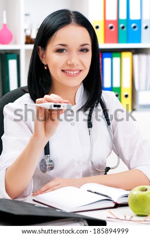 Happy young female doctor giving pregnancy test, looking at camera