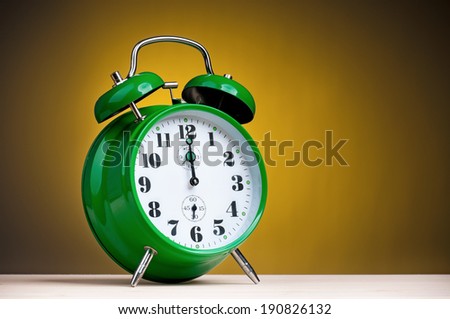Big green alarm clock on dark yellow background