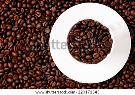 White coffee cup on coffee beans - top view - focus on cup
