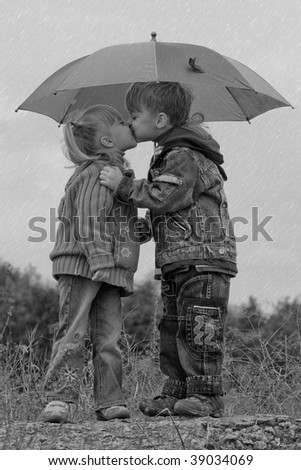 Little boy kiss girl, under umbrella in autumn day