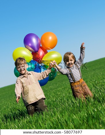 Happy girl and boy with balloons walking on the spring field