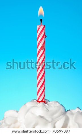 Lit birthday candle on blue background