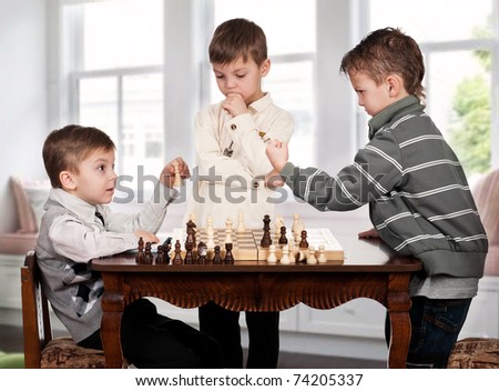 Three twin brothers playing chess game in room