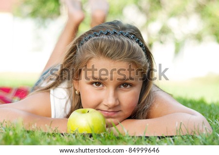 Portrait of little girl with green apple outdoor