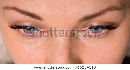 Close-up face of beautiful young woman with beautiful blue eyes and big pretty eyelashes and eyebrows. Macro of human eye - open.