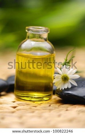 fine image of massage oil with zen stones, white flower on woven wicker mat