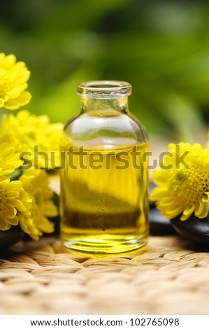 massage oil with zen stones, yellow flower on woven wicker mat