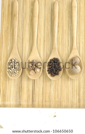 Assortment of spices in a wooden spoons on wooden board