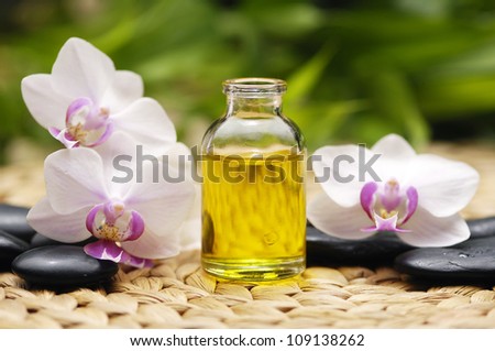 Massage oil and stones with white orchid with stones on mat