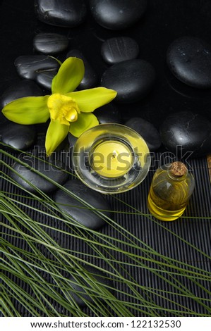 Green orchid with massage oil and candle with plant leaf
