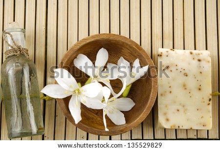 Bar of natural handmade soap with massage oil ,flower in bowl on wooden mat