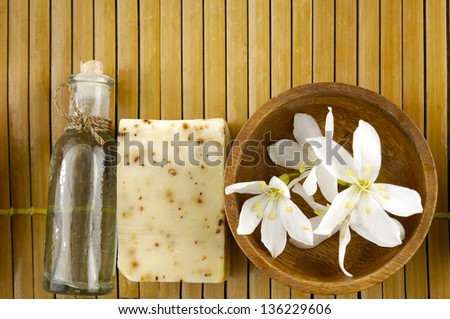 Bar of natural handmade soap with massage oil ,flower in bowl on wooden mat